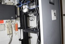 Rows of blue network cables connect servers inside a modern data centre room.